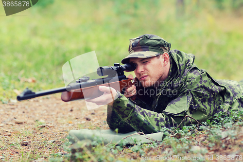 Image of young soldier or hunter with gun in forest