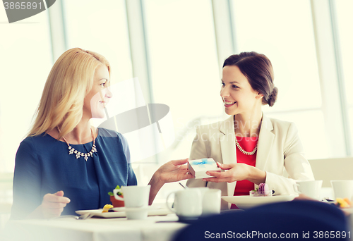 Image of happy women giving birthday present at restaurant