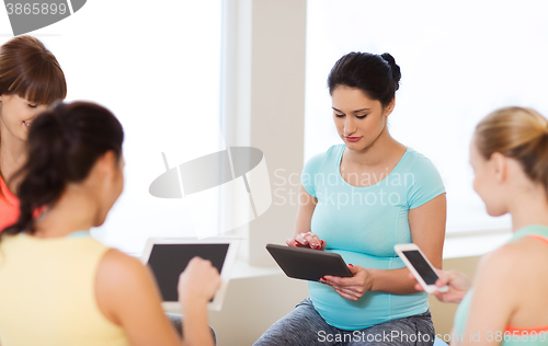 Image of happy pregnant women with gadgets in gym