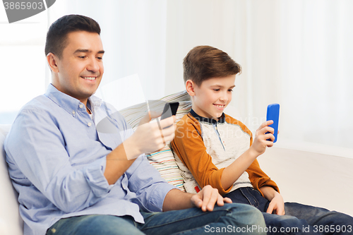 Image of happy father and son with smartphones at home