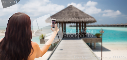 Image of young woman taking selfie with smartphone