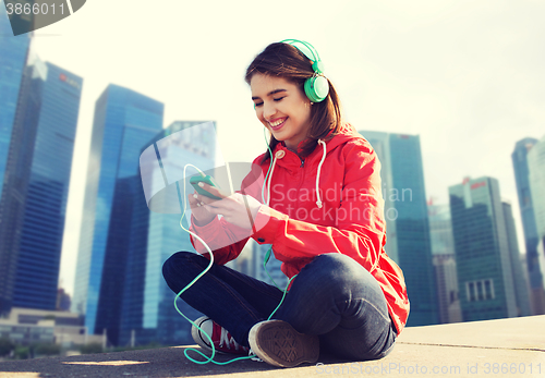 Image of happy young woman with smartphone and headphones