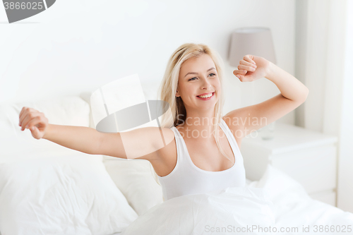 Image of young woman stretching in bed after waking up