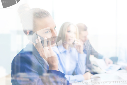 Image of smiling business team with smartphones in office