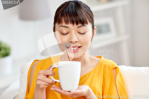 Image of happy asian woman drinking from tea cup