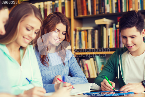 Image of happy students writing to notebooks in library