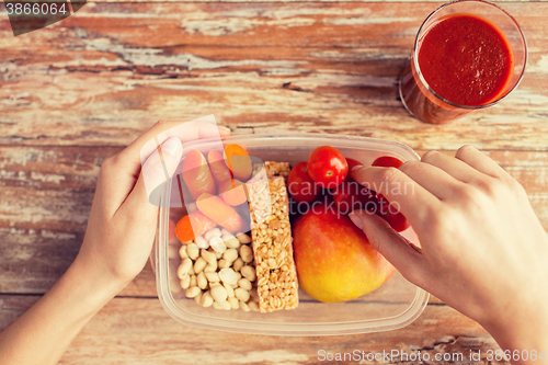 Image of close up of hands with vegetarian food in box