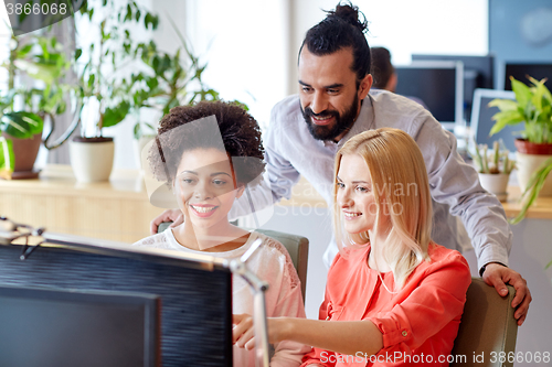 Image of happy creative team with computer in office