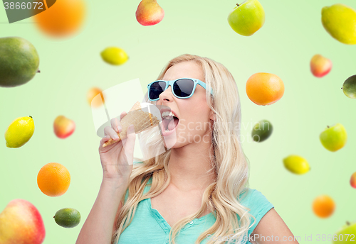 Image of happy young woman in sunglasses eating ice cream