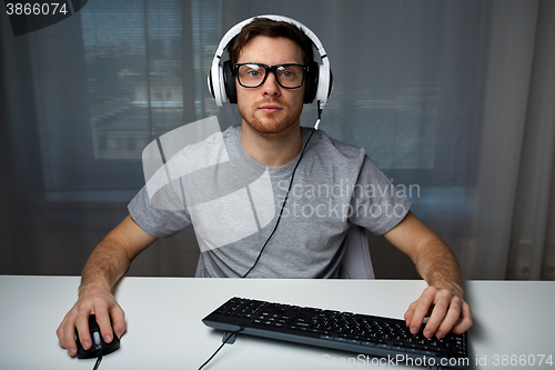 Image of man in headset playing computer video game at home