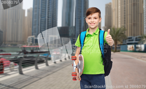 Image of boy with backpack and skateboard showing thumbs up