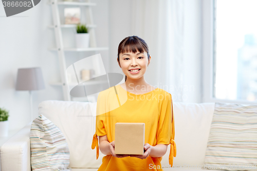 Image of happy asian young woman with parcel box at home