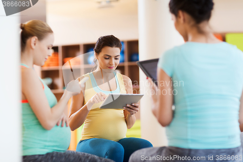 Image of happy pregnant women with gadgets in gym