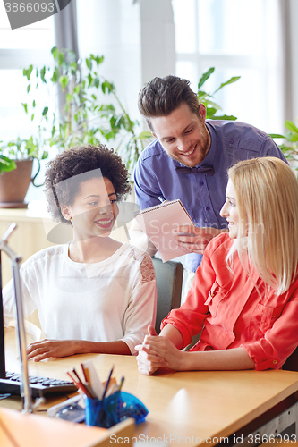 Image of happy creative team with computer in office