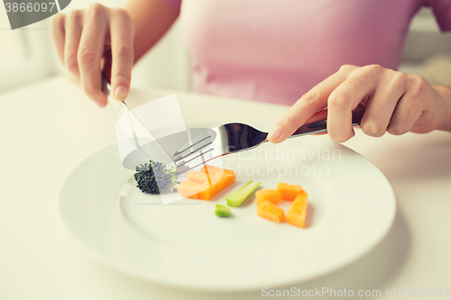 Image of close up of woman hands eating vegetables