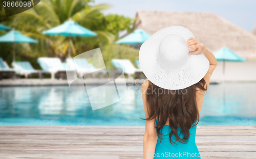 Image of woman in swimsuit and sun hat from back over beach