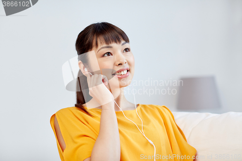 Image of happy asian woman with earphones listening music