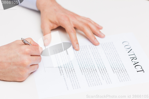 Image of close up of male hands signing contract document