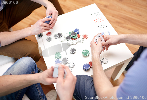 Image of close up of male friends playing cards at home