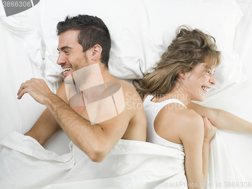 Image of attractive couple in love laughing in bed