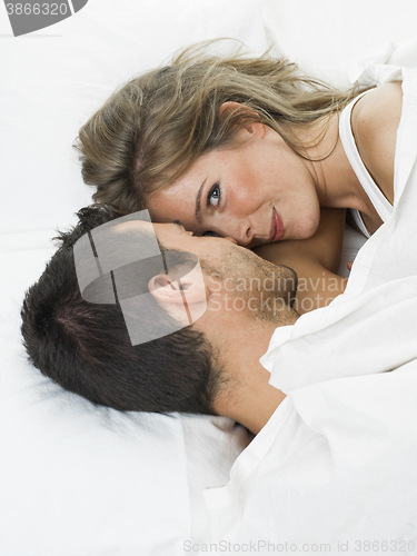 Image of attractive couple in love under white bed sheets