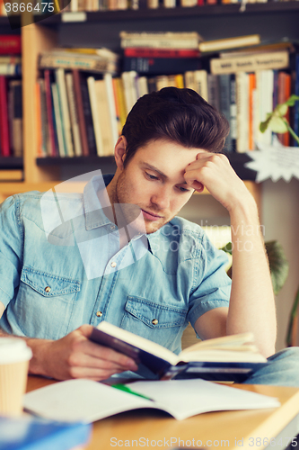 Image of male student reading book in library