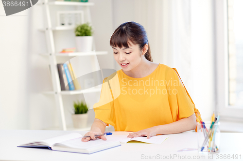 Image of happy asian young woman student learning at home