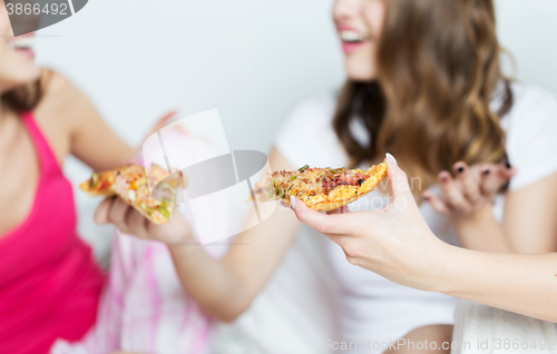 Image of happy friends or teen girls eating pizza at home