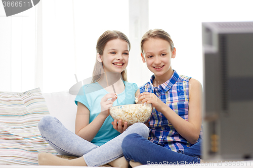 Image of happy girls with popcorn watching tv at home