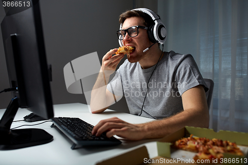 Image of man in headset playing computer video game at home