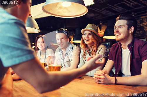 Image of happy friends drinking beer and talking at bar