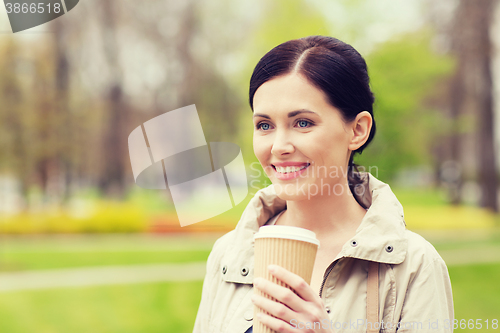 Image of smiling woman drinking coffee in park