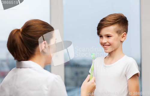 Image of doctor with toothbrush and happy boy in clinic