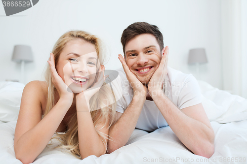 Image of happy couple lying in bed at home