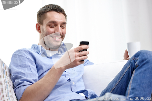 Image of smiling man with smartphone at home