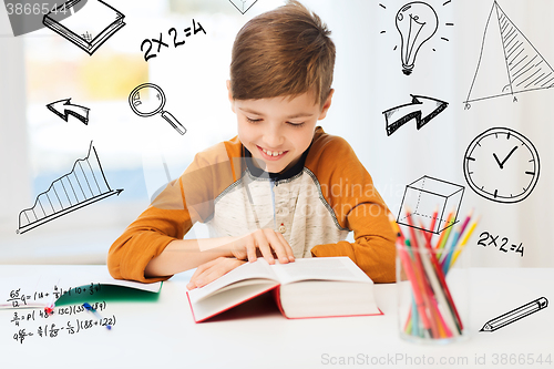 Image of smiling, student boy reading book at home