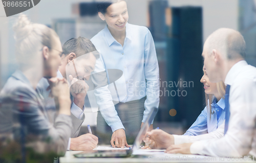 Image of smiling female boss talking to business team