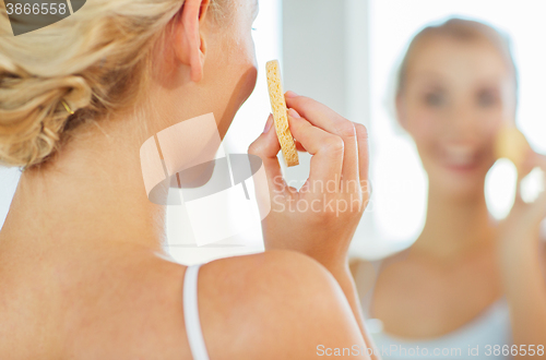 Image of close up of woman washing face with sponge at home