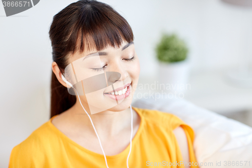 Image of happy asian woman with earphones listening music