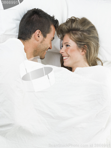 Image of attractive couple in love under white bed sheets
