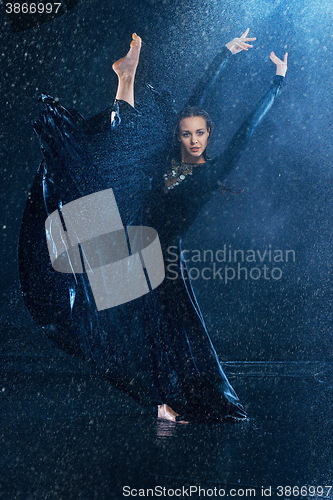 Image of The young beautiful modern dancer dancing under water drops