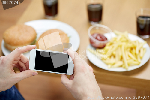 Image of close up of man with smartphone picturing food