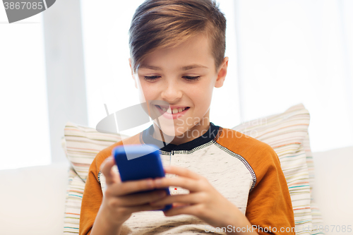Image of boy with smartphone texting or playing at home