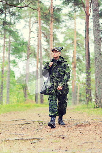 Image of young soldier or hunter with gun in forest