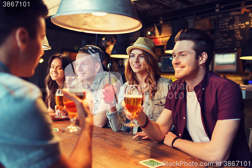 Image of happy friends with drinks talking at bar or pub