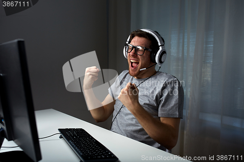 Image of man in headset playing computer video game at home