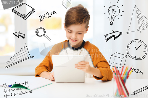 Image of smiling boy with tablet pc and notebook at home