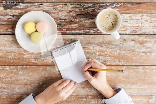 Image of close up of hands, notebook, coffee and cookies