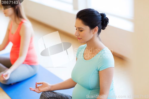 Image of happy pregnant women exercising yoga in gym