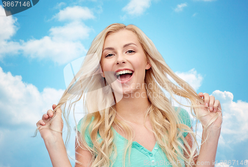 Image of smiling young woman holding her strand of hair